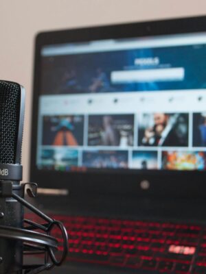 Close-up of a microphone and laptop on a desk suitable for home recording or podcasting.