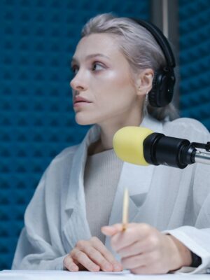 Confident woman wearing headphones hosting a podcast in a soundproof studio.