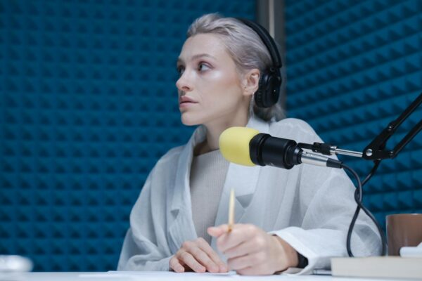 Confident woman wearing headphones hosting a podcast in a soundproof studio.