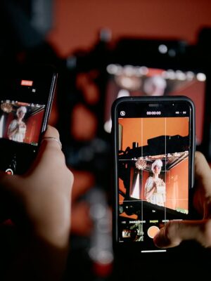 Hands holding smartphones recording a scene indoors with professional equipment.