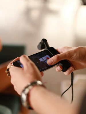 Hands using a smartphone with a microphone attachment for recording indoors.