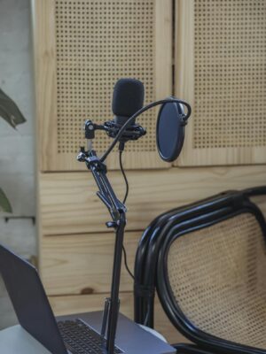 Opened netbook placed on table near tripod with microphone during podcast recording in cozy studio